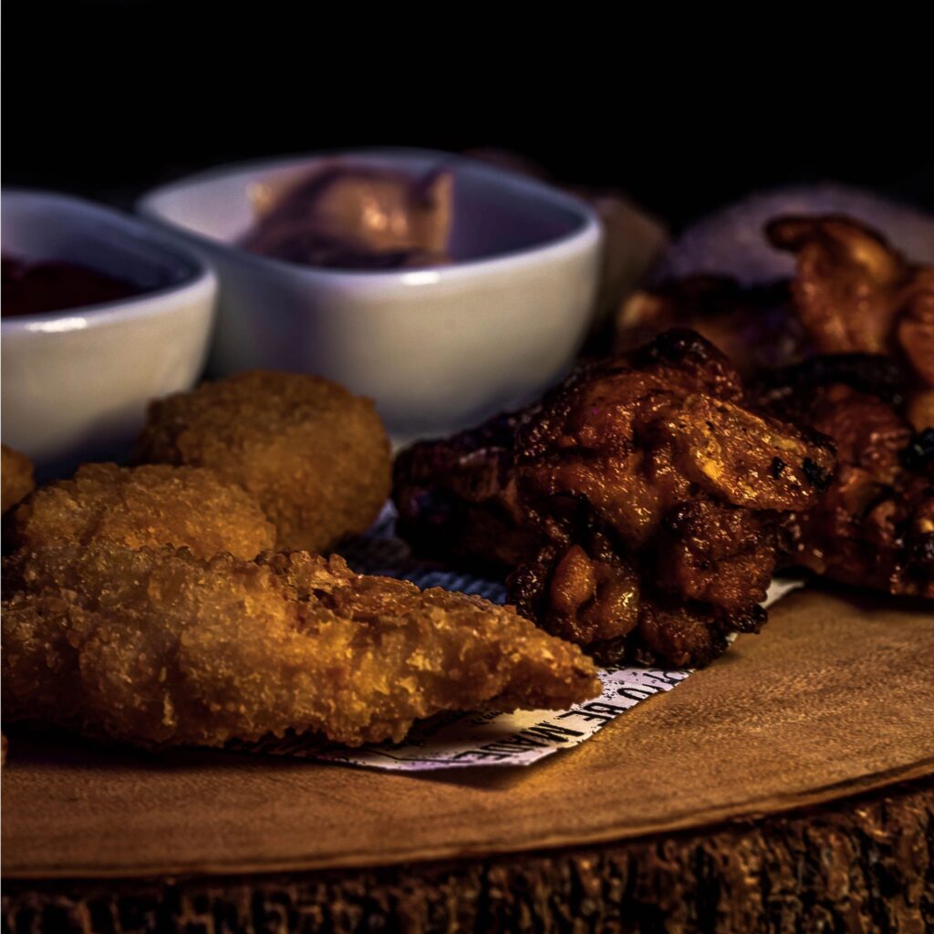 Assorted LA-style street food platter with fried bites and dipping sauces on a dark, premium background