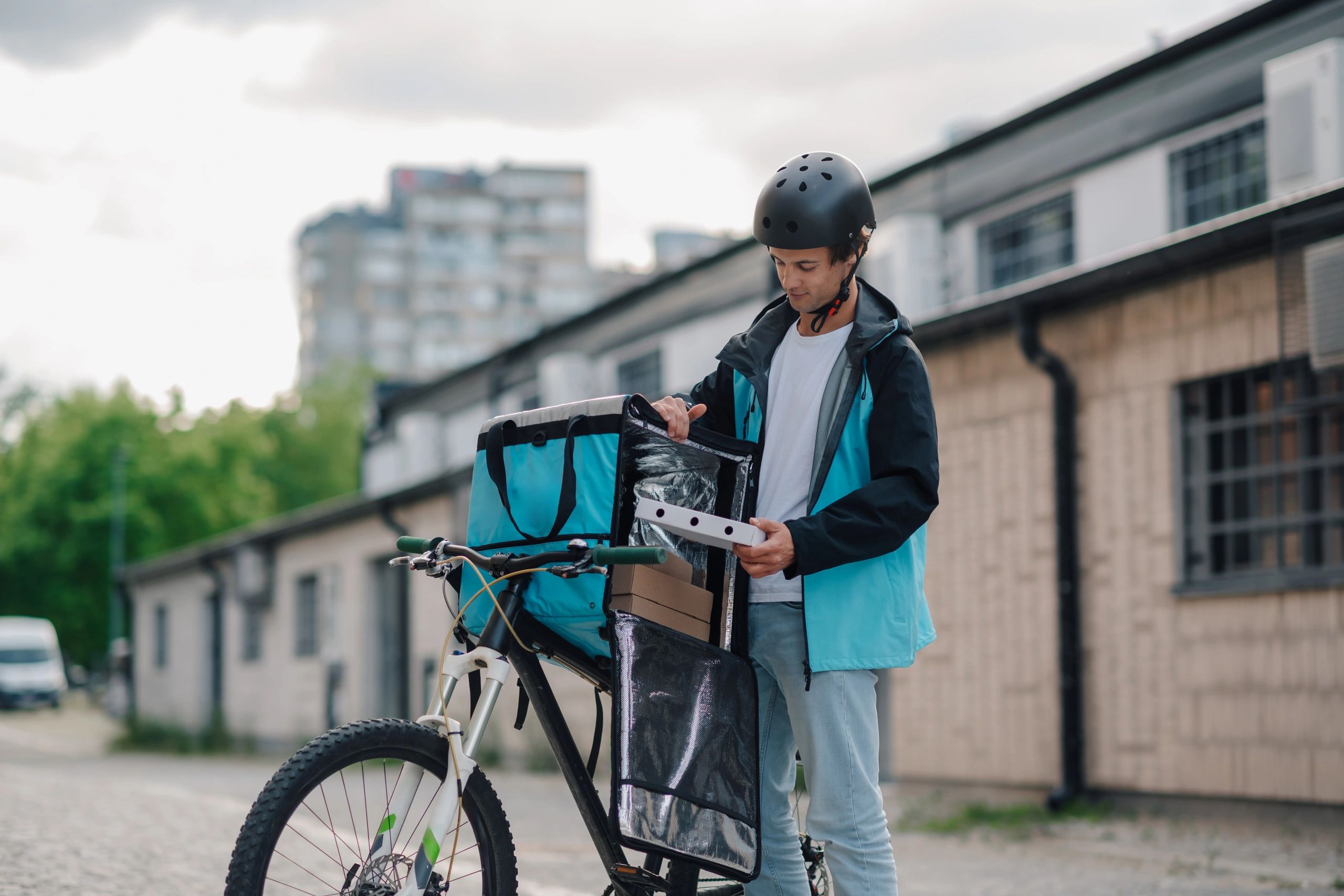 Courier preparing a food delivery order with a bicycle in the city