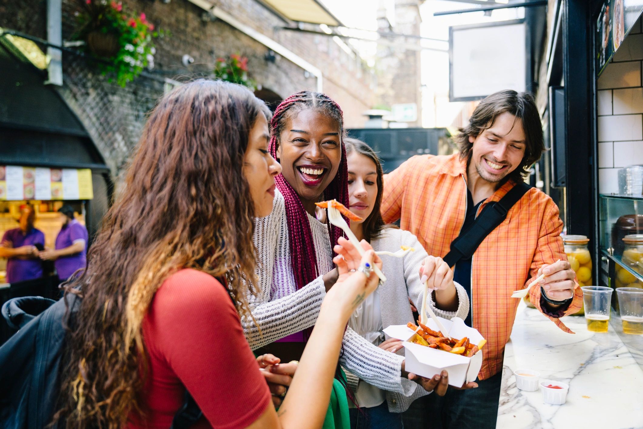 People ordering and enjoying food at an outdoor market stall